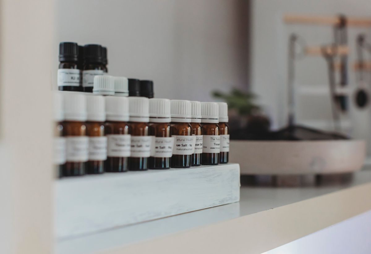 Rows of amber homeopathic remedy bottles with The Natural Health Option labels on a clinic shelf