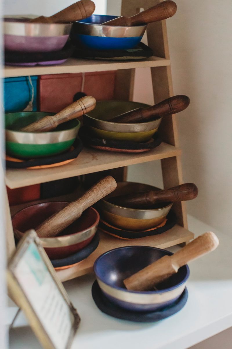 Coloured singing bowls and wooden strikers on a ladder shelf