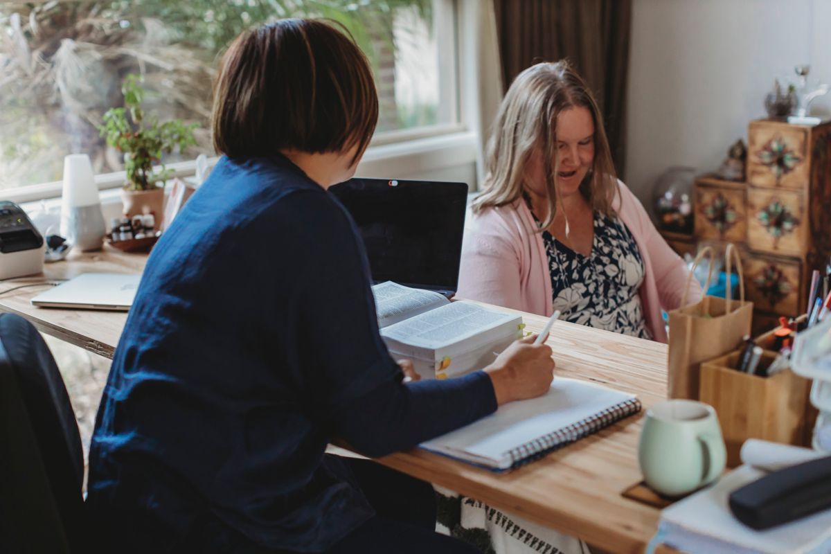 Van taking notes at her desk during a consultation with a smiling client
