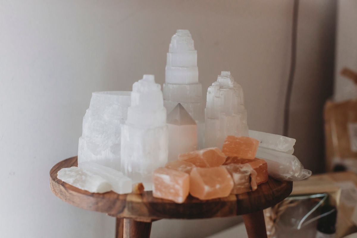 Selenite towers and peach calcite on a small wooden stool in the clinic