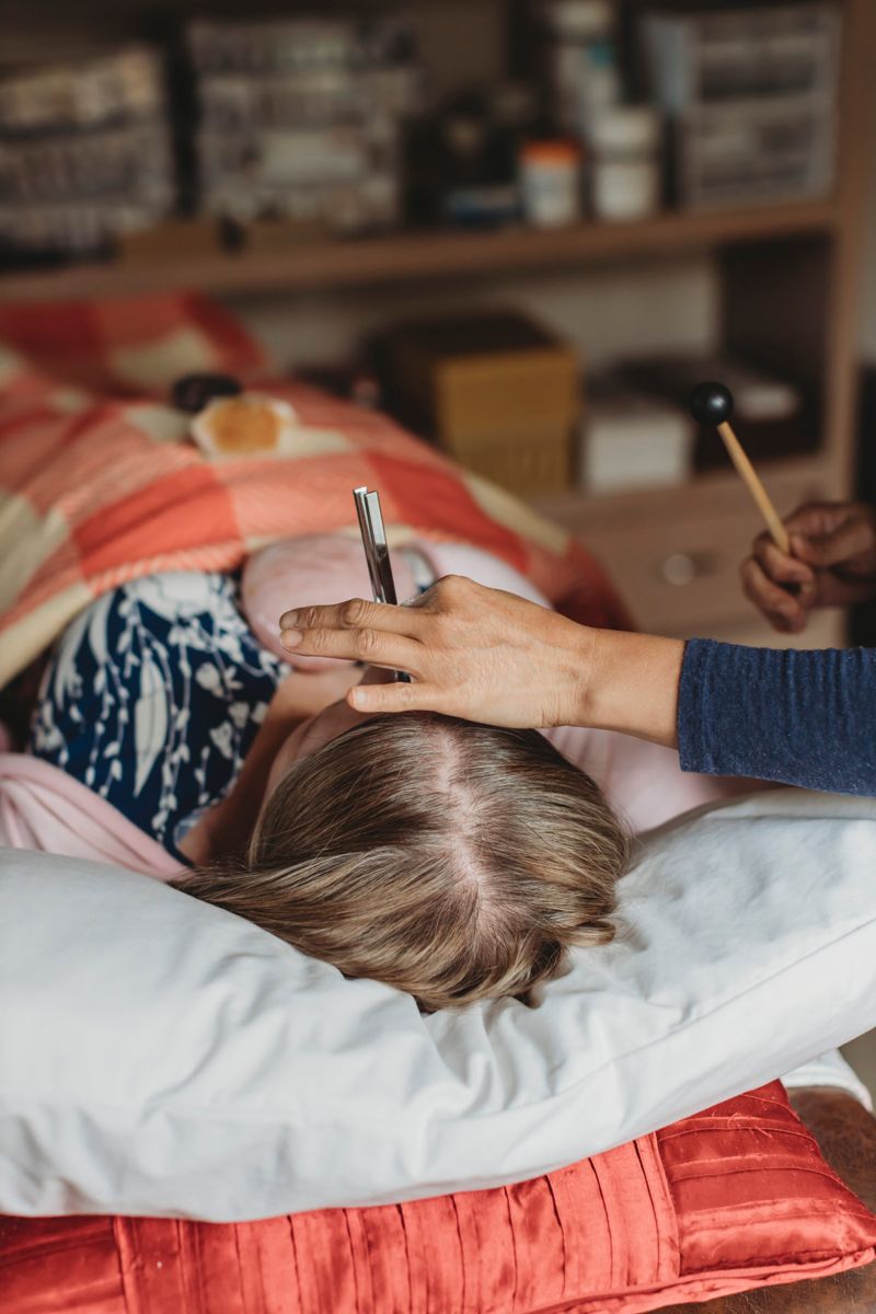 Van smiling as she moves her hands above a resting client