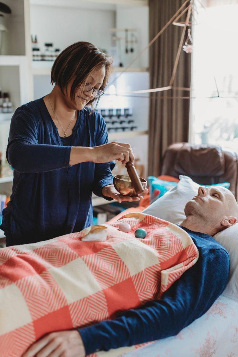 Van playing a singing bowl over a resting client