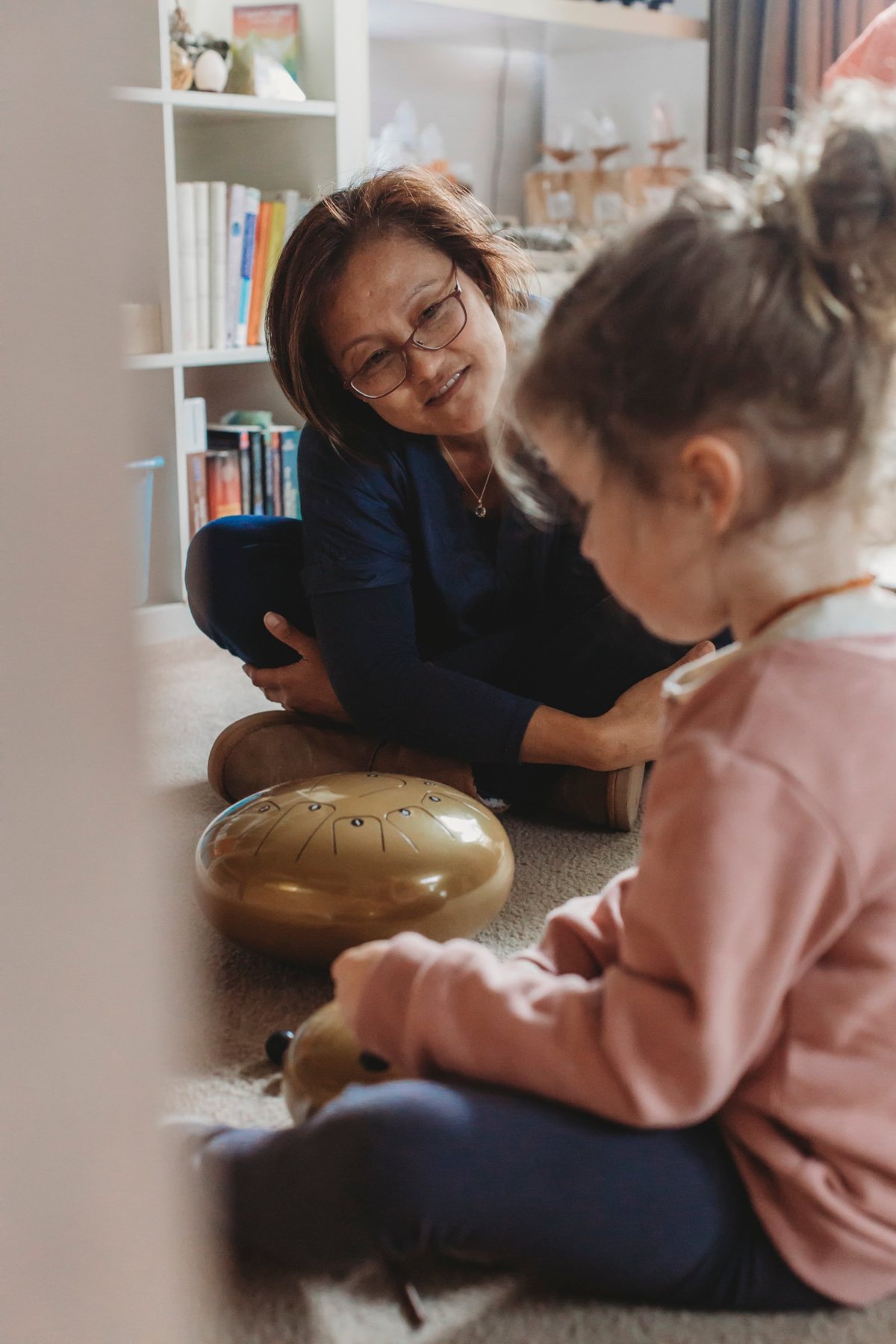 Van sitting on the floor guiding a young client with a tongue drum